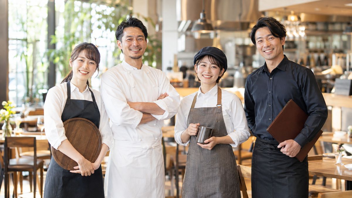 レストランのホールに並んで笑顔で迎えるホールスタッフ・料理人・カフェスタッフ・店舗スタッフ